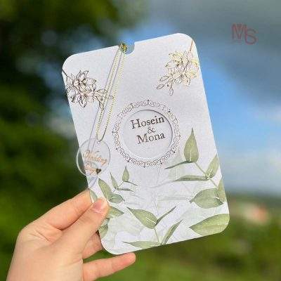 کارت عروسی مدل S386 | طراحی لوکس و خاص برای روزی بی‌نظیرکارت عروسی یکی از مهم‌ترین اجزای هر مراسم عروسی است که نخستین تصویری که از جشن شما در ذهن مهمانانتان نقش می‌بندد را ترسیم می‌کند. به همین دلیل، انتخاب کارت عروسی مناسب با طراحی زیبا و منحصر به فرد می‌تواند شروعی خاص و خاطره‌انگیز برای جشن شما باشد. کارت عروسی مدل S386 از منش استور با ویژگی‌هایی همچون پاکت از جنس مقوا، لایی کارت از جنس طلق، چاپ طلاکوب، برش خاص، و طراحی لوکس و خاص، یک انتخاب ایده‌آل برای کسانی است که به دنبال کارت عروسی‌ای منحصر به فرد، شیک و با کیفیت هستند.